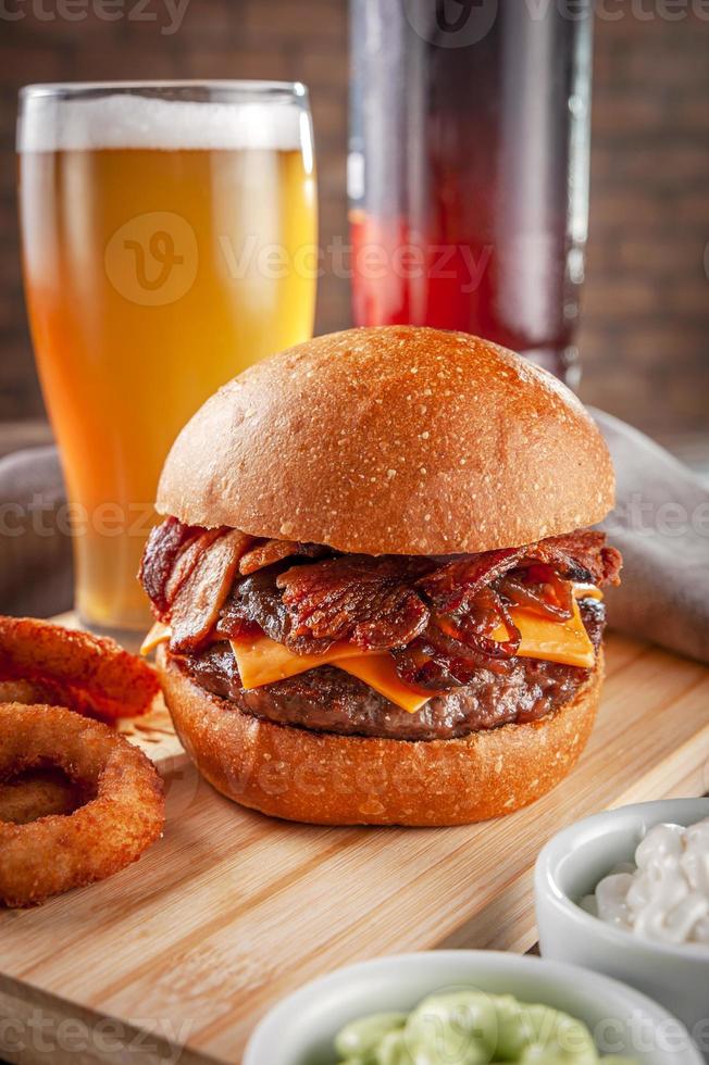 deliciosa hamburguesa de tocino con aros de cebolla y cerveza. foto