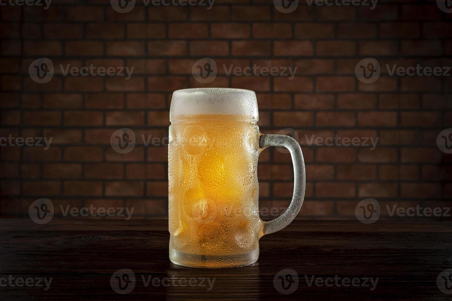 Isolated sweaty glass of refreshing amber ale draft beer with brick wall background. photo