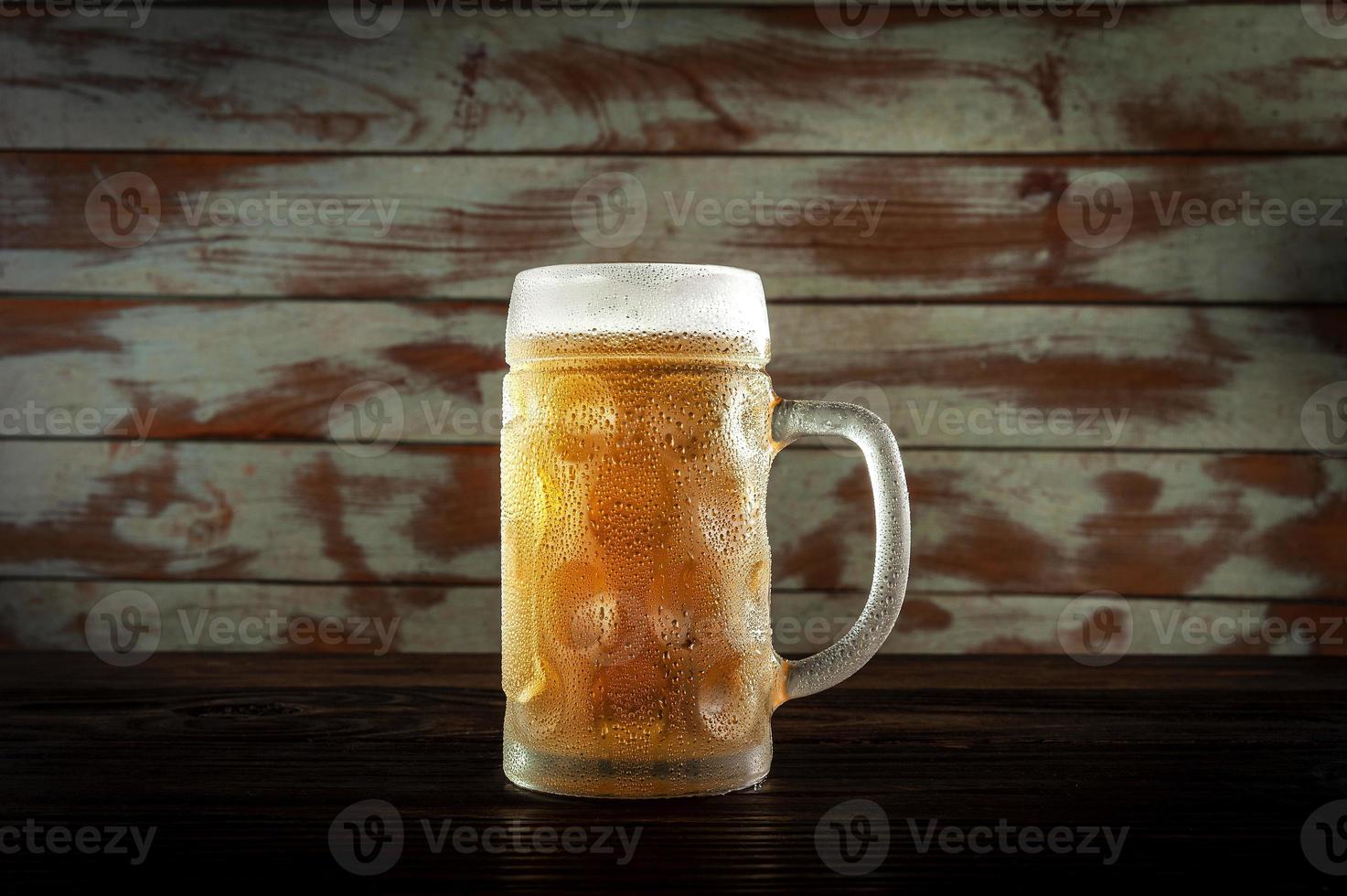 Aislado sudoroso vaso de refrescante cerveza de barril pilsen con fondo de pared de madera. foto