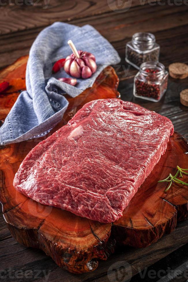 Raw marble denver beef on a wood resined cutting board with spices and rosemary photo