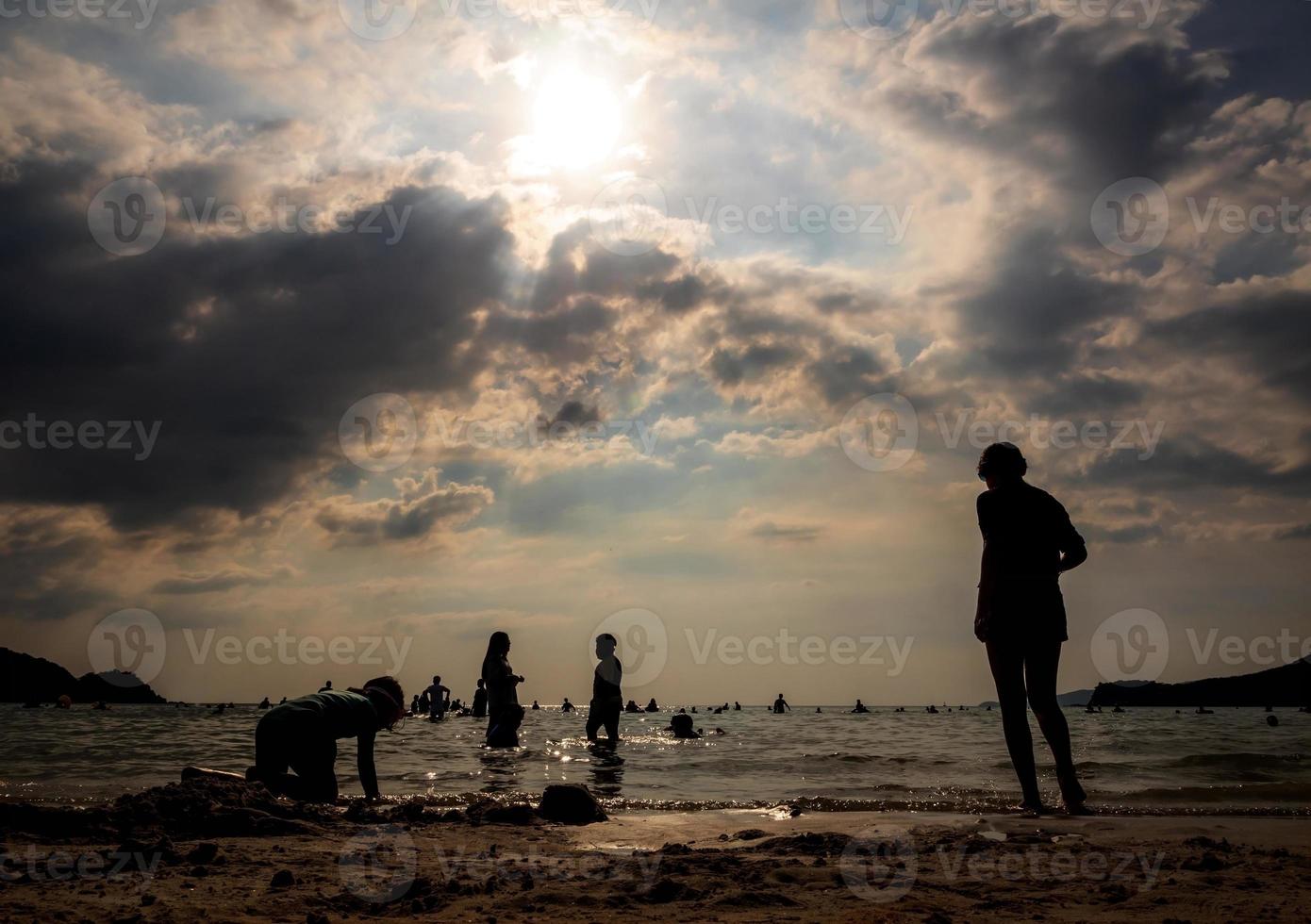 Silhouettes of people playing in the sea at a public beach photo