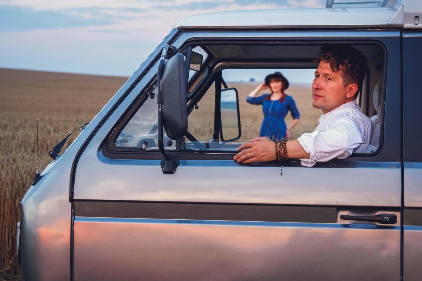 retrato, de, hombre, coche, y, hermoso, mujer joven, en, vestido, y, sombrero, ambulante, por, campo de trigo, contra, fondo del cielo foto