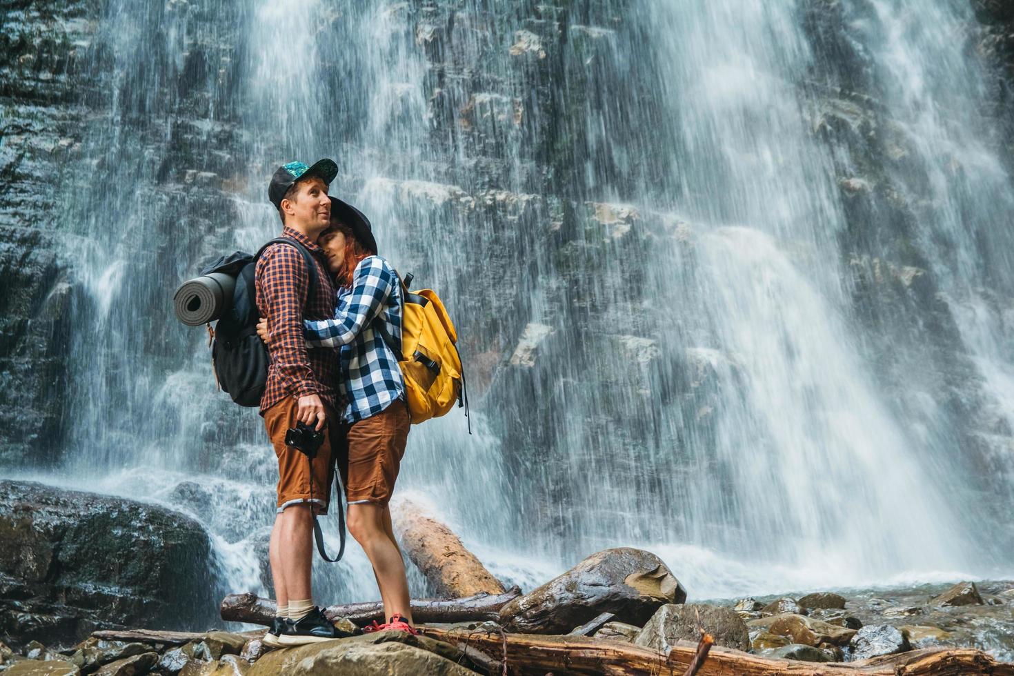 Hombre y mujer excursionistas trekking por un camino rocoso con el telón de fondo de una cascada y rocas foto