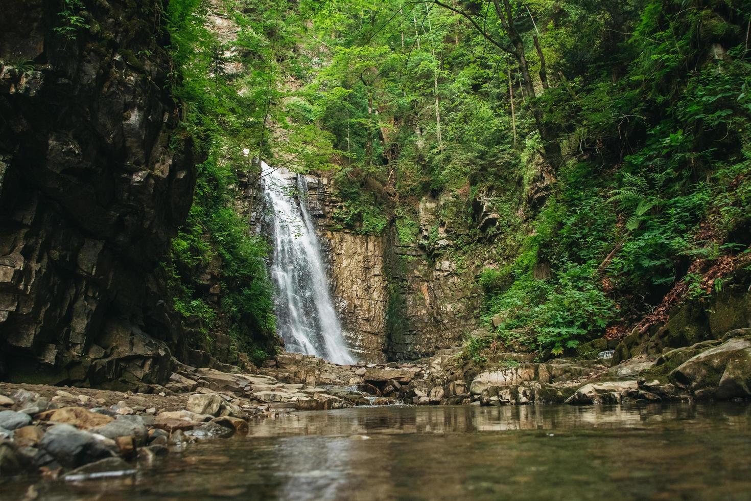 Waterfall with a lake among rocks and forest photo