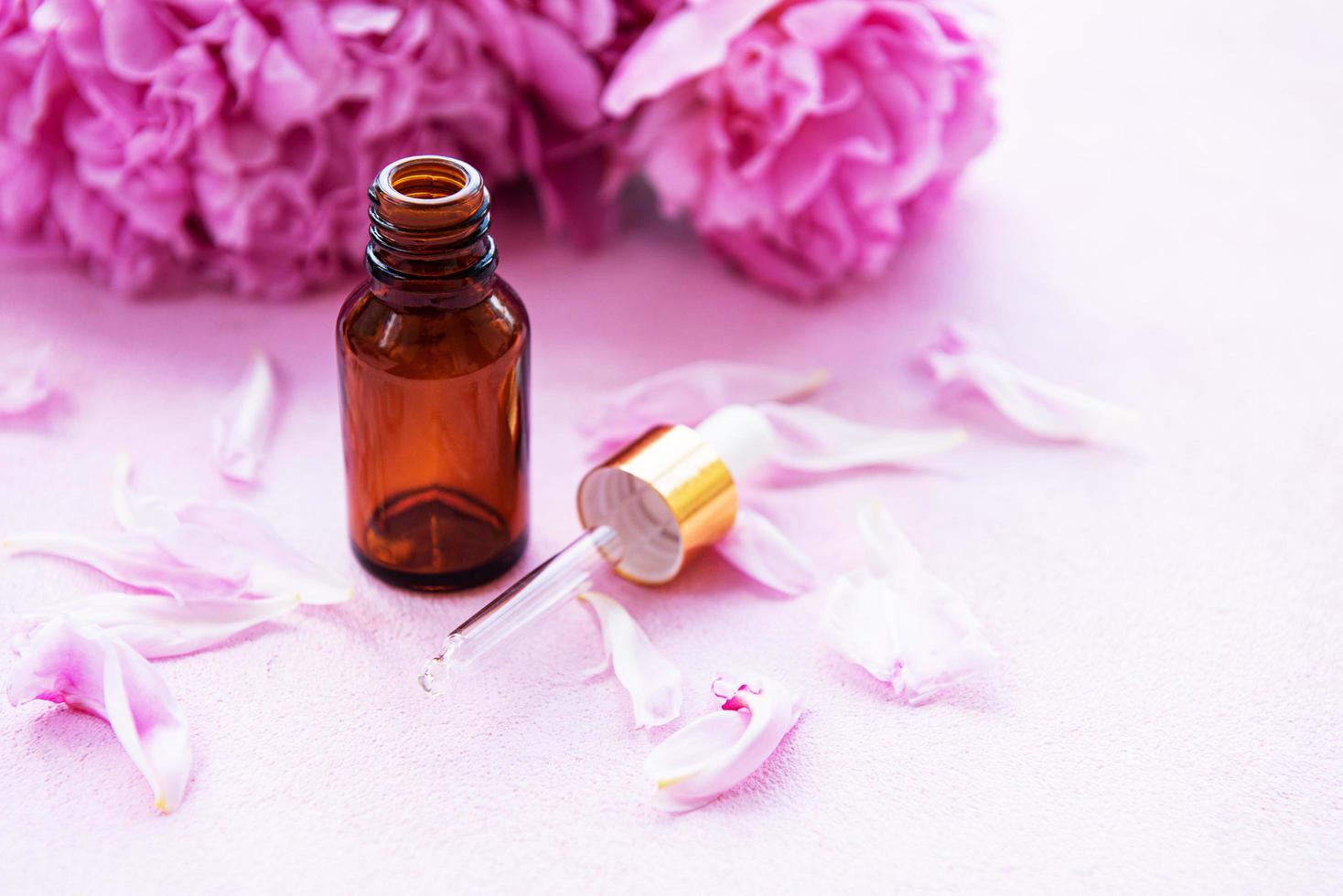 Aromatherapy essentials oils and pink peonies photo