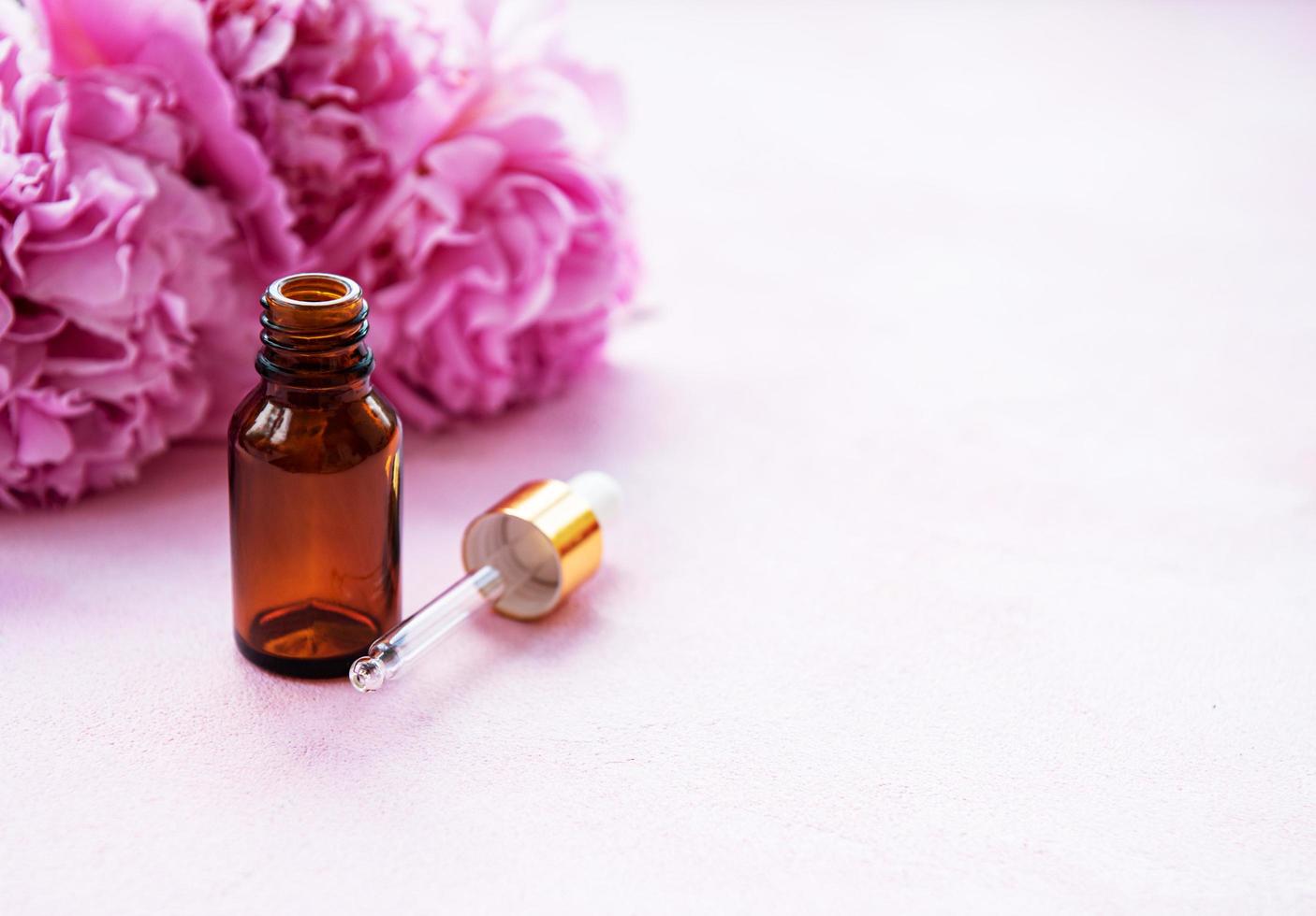 Aromatherapy essentials oils and pink peonies photo