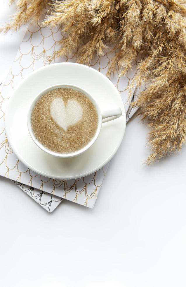 espacio de trabajo de escritorio de oficina con cuaderno, café y pasto de la pampa foto