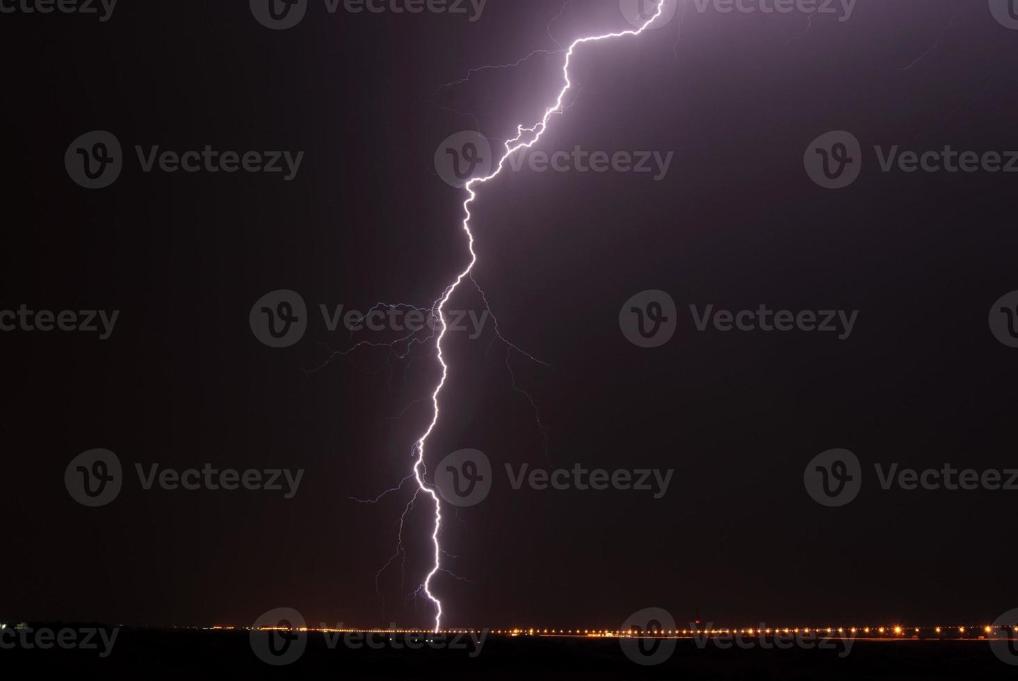 Landscape with lightning striking behind a dead tree trunk photo