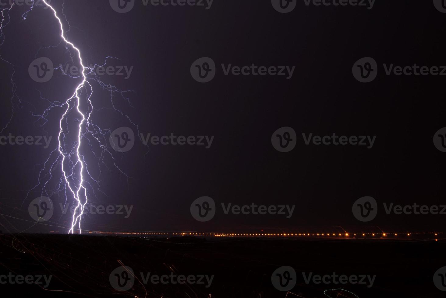 Landscape with lightning striking behind a dead tree trunk photo