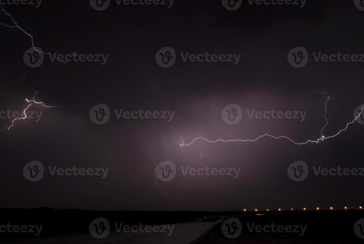 Landscape with lightning striking behind a dead tree trunk photo