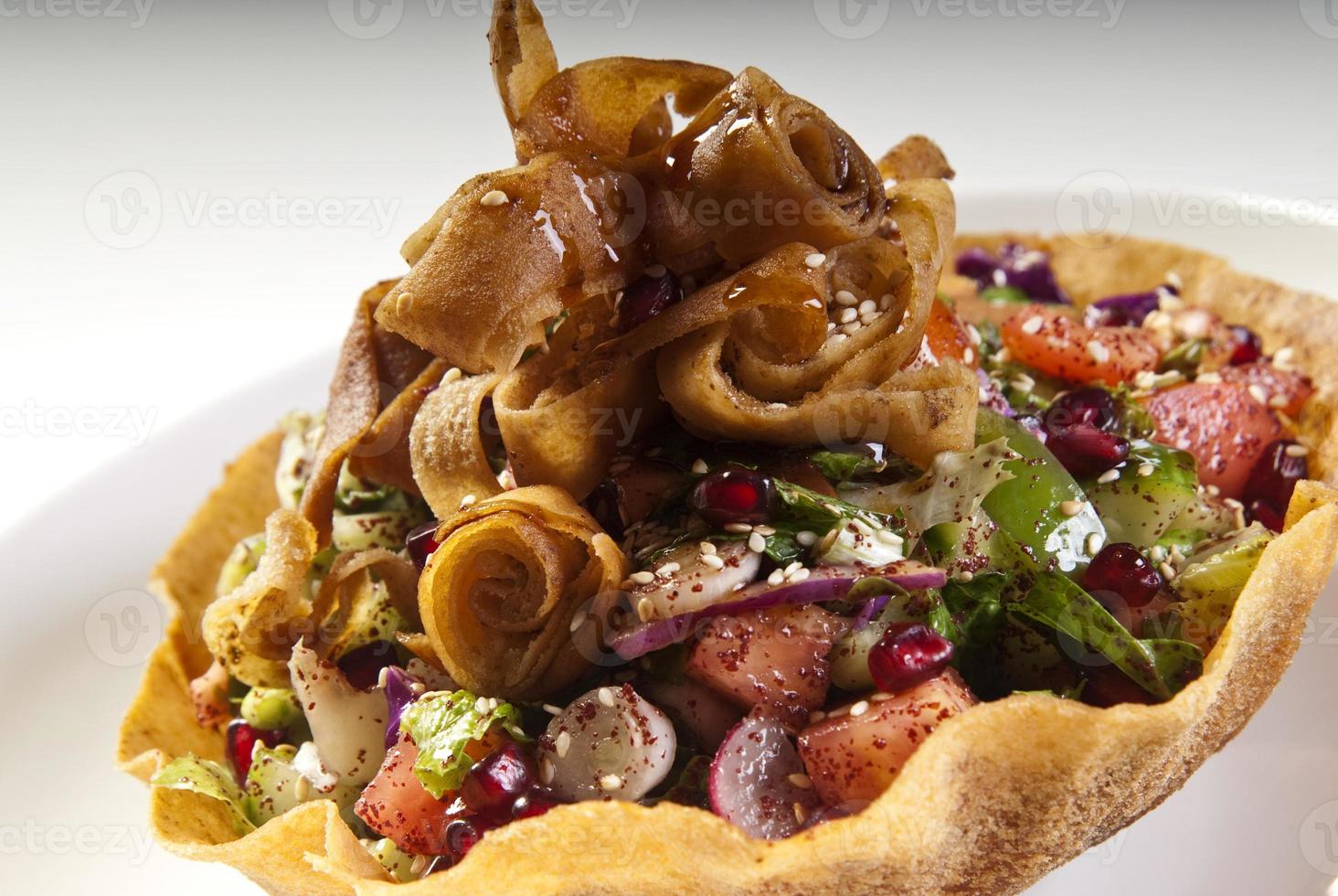 Delicious Fattoush or Arab salad with pita croutons, fresh vegetables and herbs, on white plate. Middle Eastern bread salad. Easy and healthy authentic recipe. photo