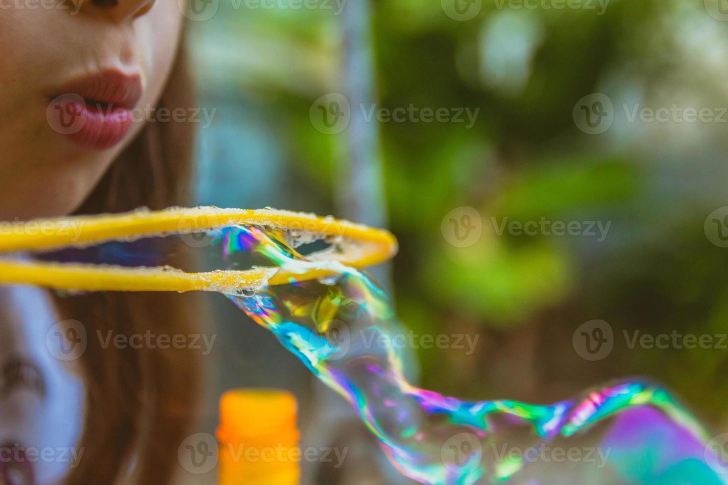 Close up of little girl blowing soap bubbles photo