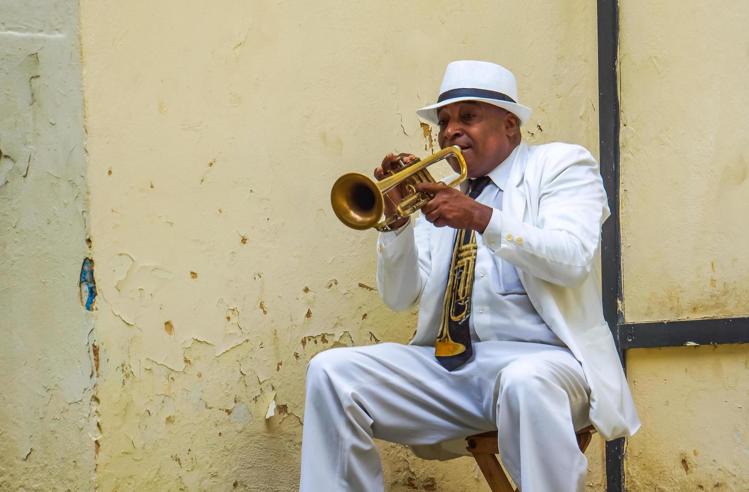 HAVANA, CUBA, JULY 4, 2017 - Unidentified man playing trumpet on the street of Havana, Cuba. Street musicians are common in Havana where they play music for tourists. photo