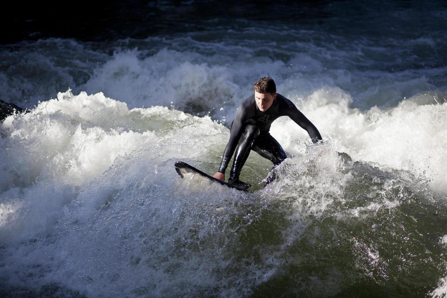 MUNICH, GERMANY, OCTOBER 23 - Unidentified surfer in the Eisbach river in English Garden in Munich, Germany at October 23, 2011. The first surfers discovered the Eisbach in the 1970's. photo