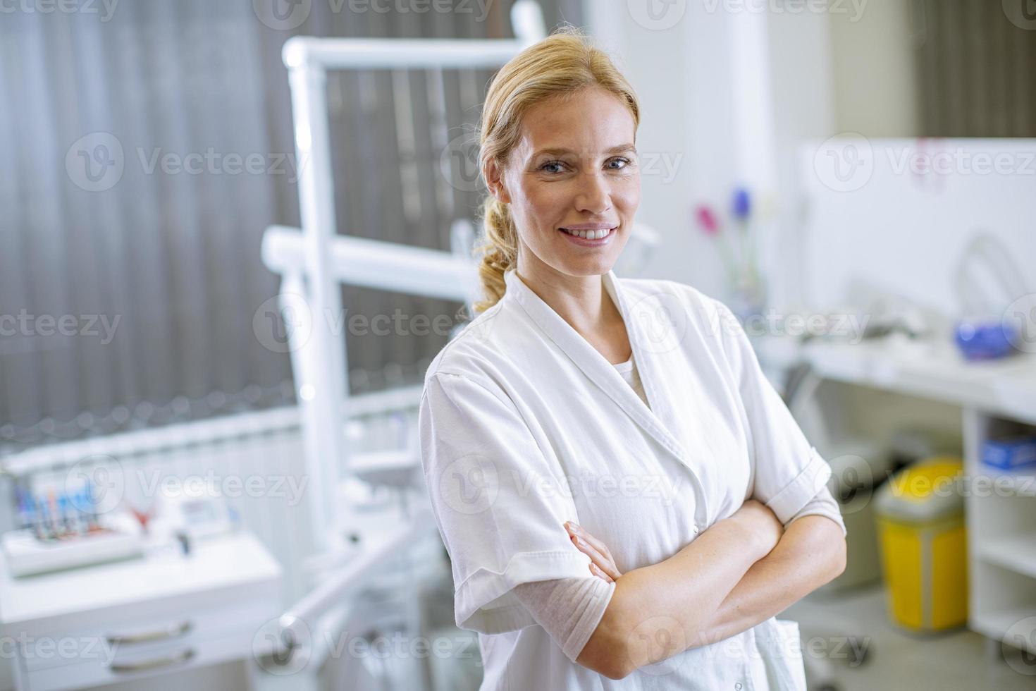 Atractiva mujer dentista posando en el consultorio dental moderno foto