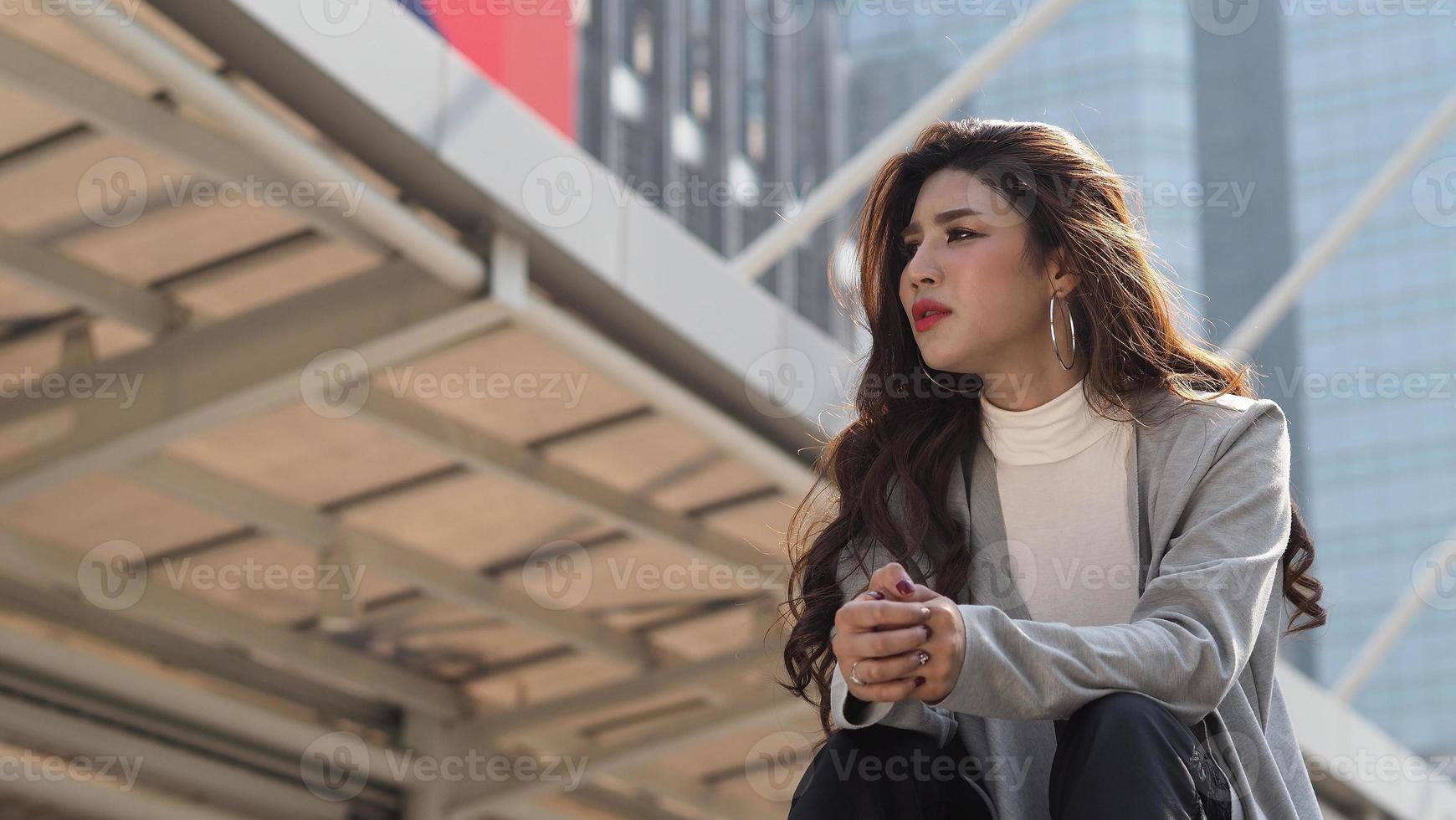 Lay off. Sacked. Fired business woman sitting on stairs of office building outside. photo