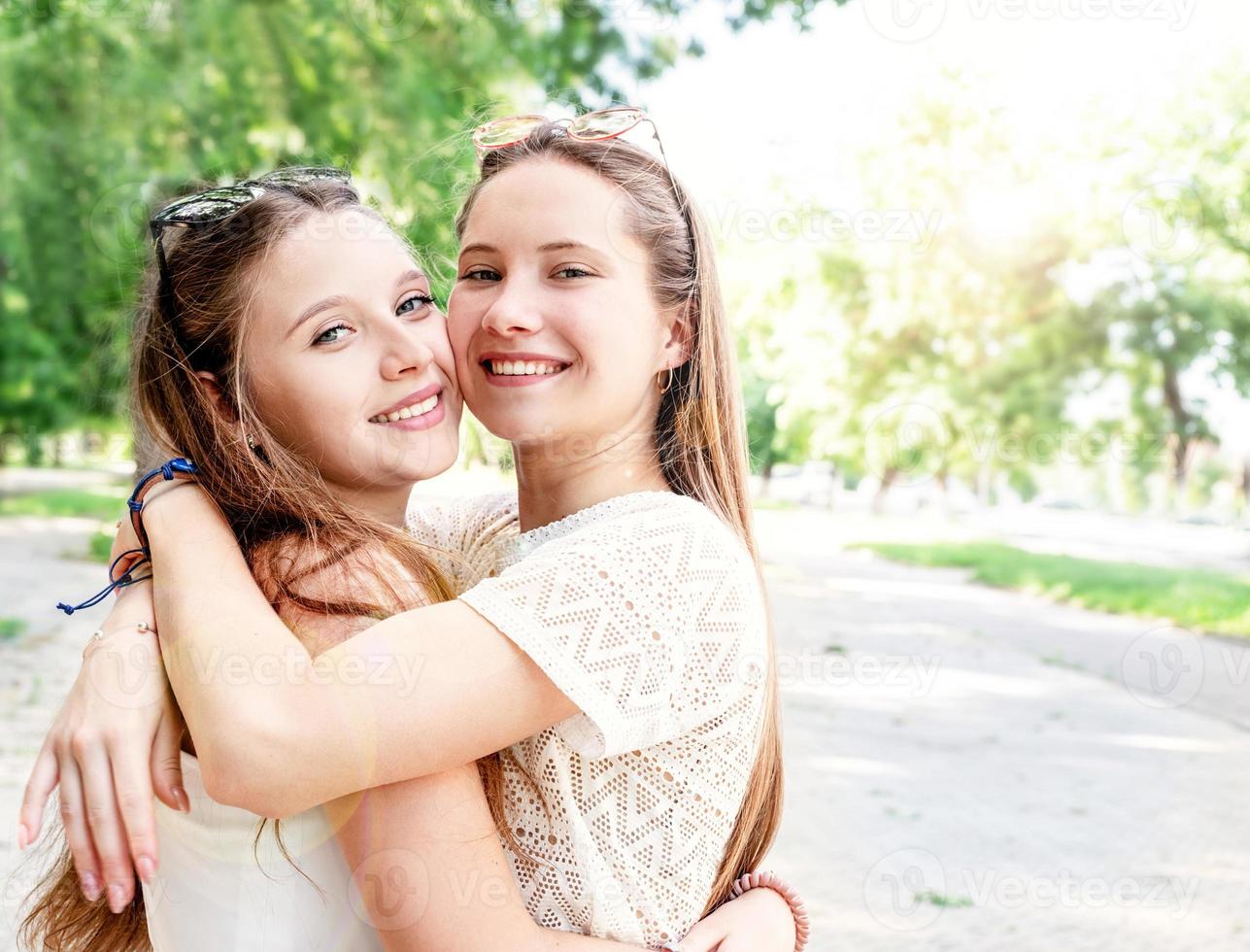 Happy girlfriends hugging together outdoors photo