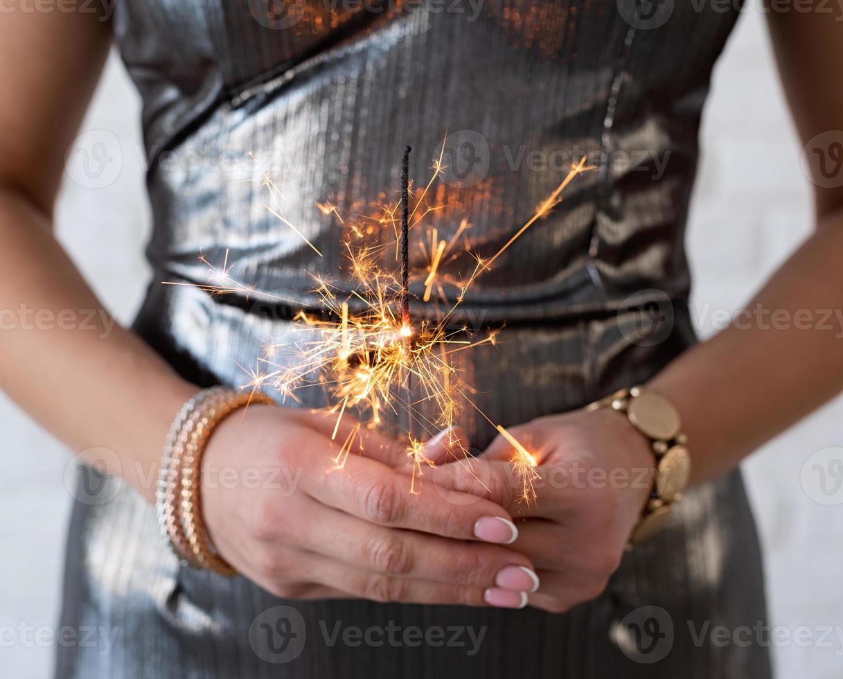 Woman in a party dress holding a sparkler in her hands photo