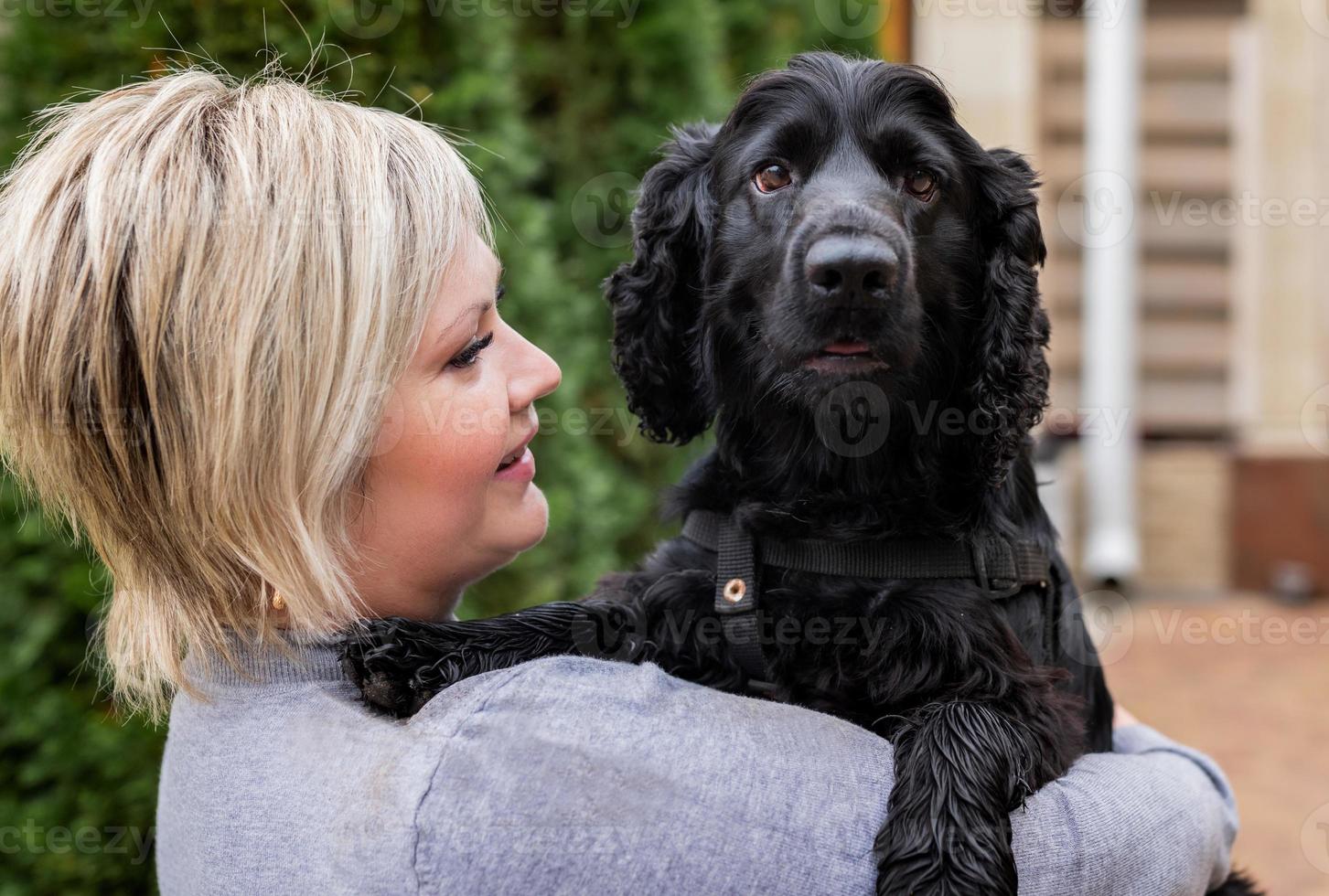 young woman holding her cocker spaniel dog outside photo