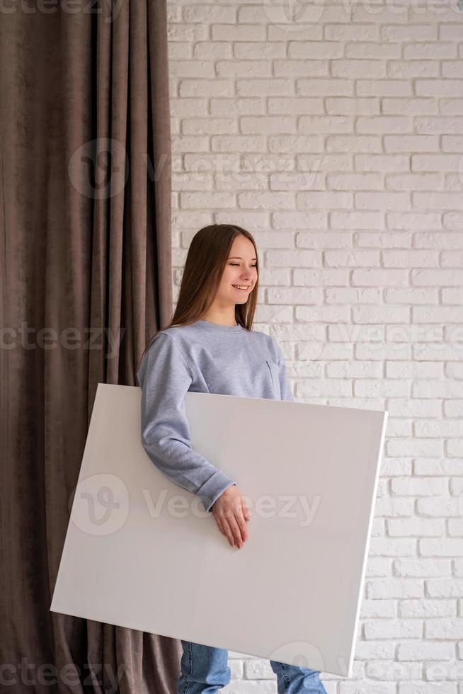 young female artist holding her canvas in the studio photo