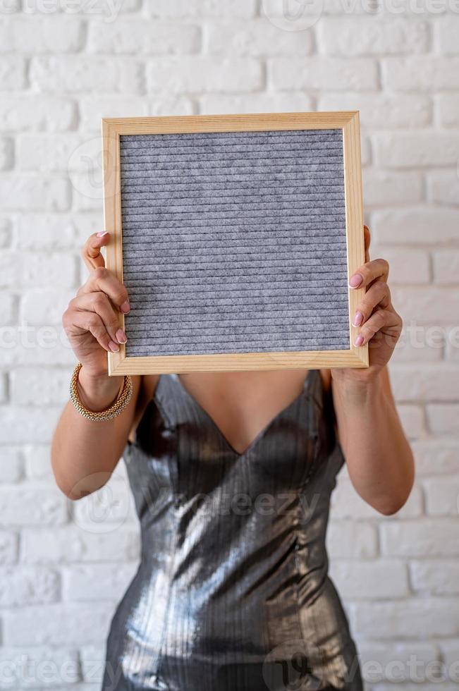 Hermosa mujer en un vestido de fiesta sosteniendo un tablero de letras de fieltro vacío foto