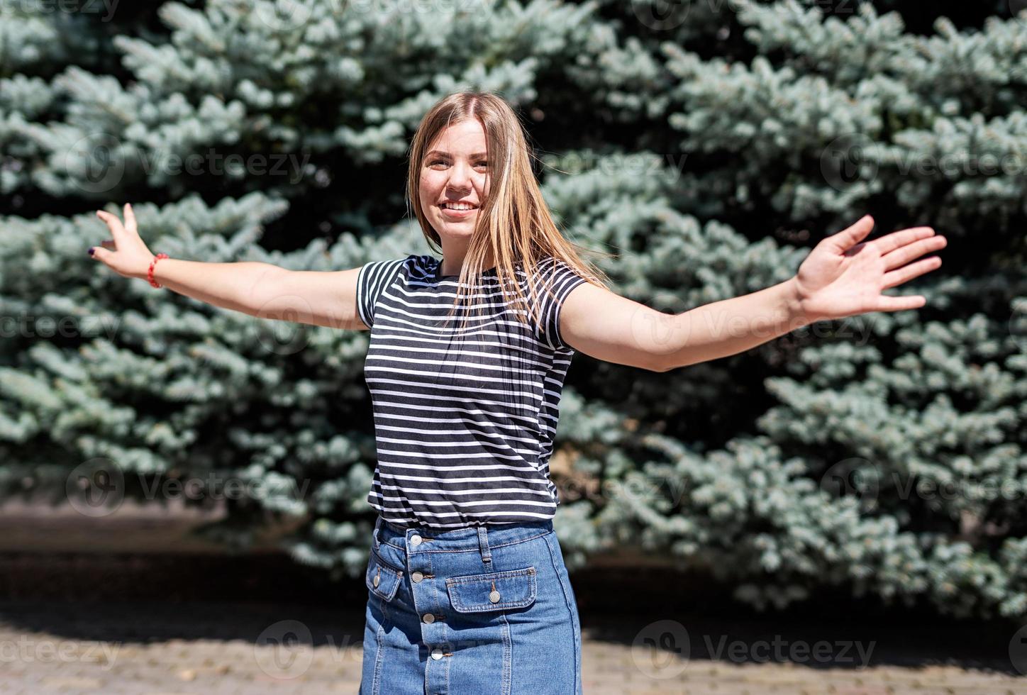 young pretty caucasian woman in casual clothes having fun turning around on fur background in the park photo