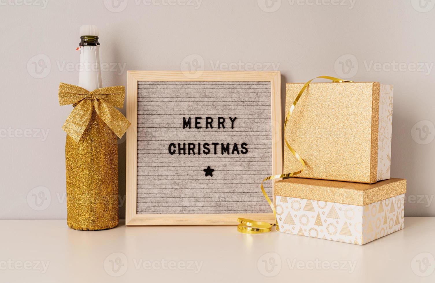 Felt letter board Merry Christmas decorated with golden champagne bottle and gift boxes photo