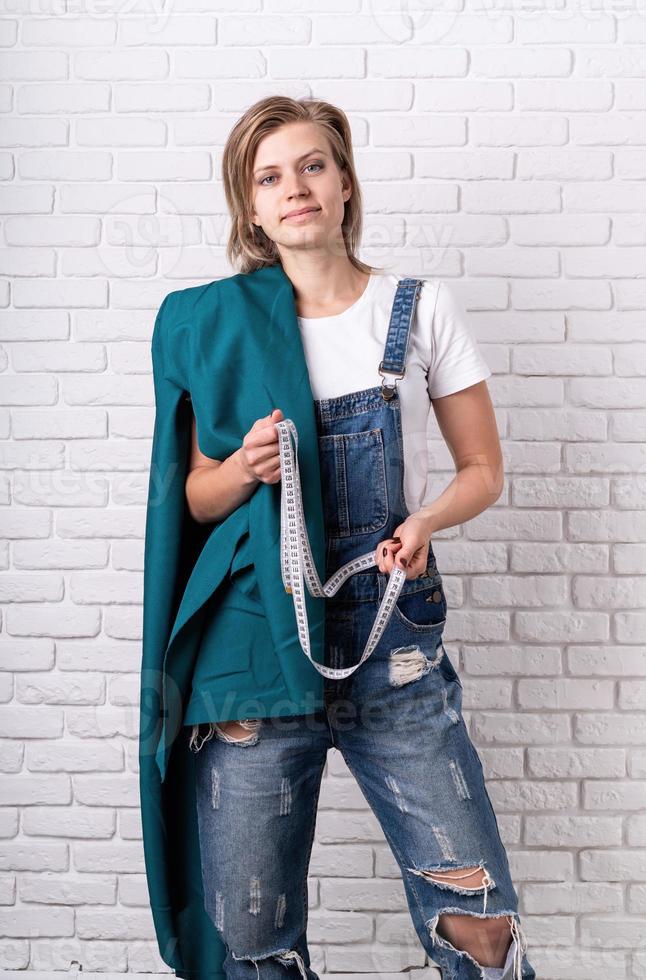 Young caucasian woman tailor holding the textile and a tape measurer photo