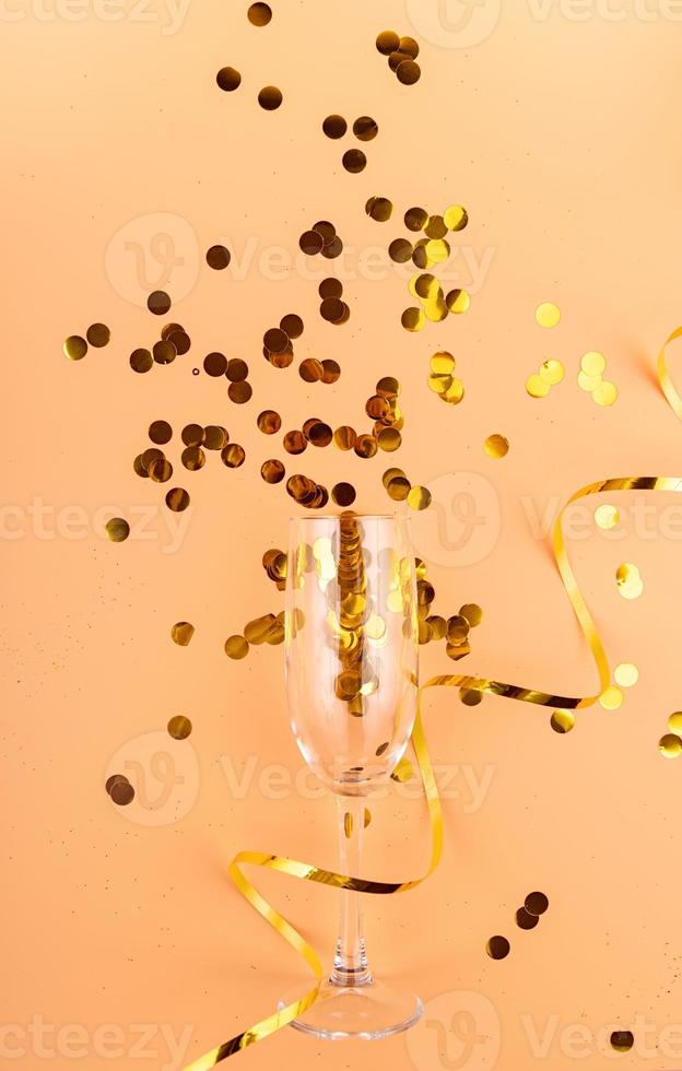 Confeti amarillo saliendo del vaso sobre fondo naranja foto