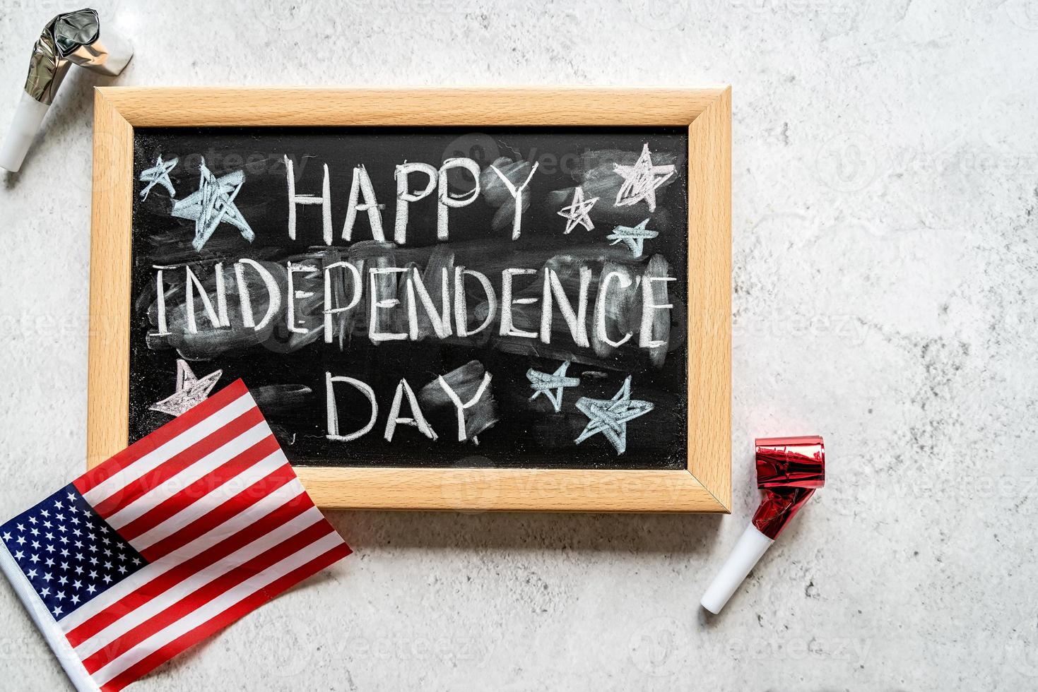 Closeup of American flag with a chalkboard with text Happy Independence Day top view photo