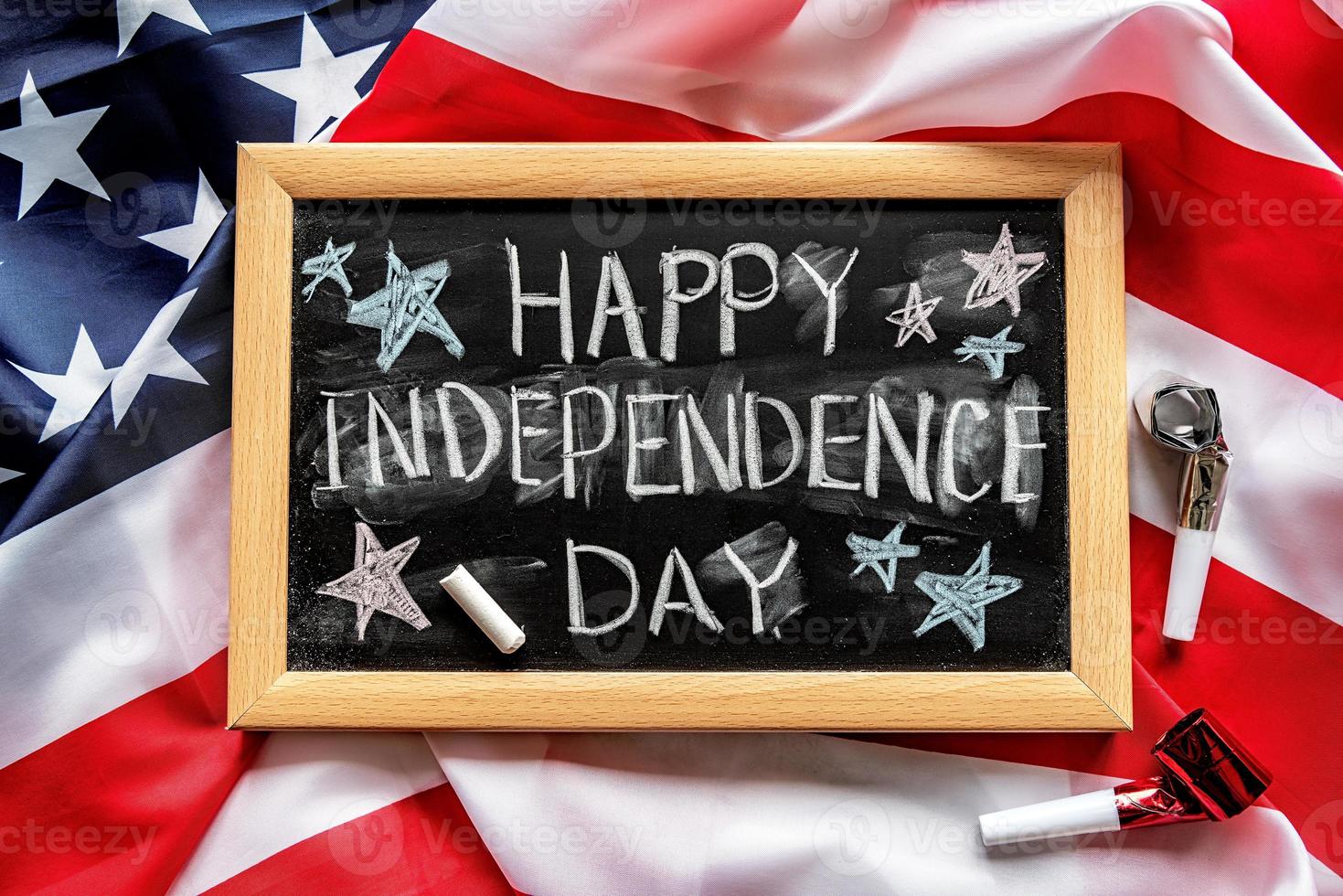 Closeup of American flag with a chalkboard with text Happy Independence Day top view photo