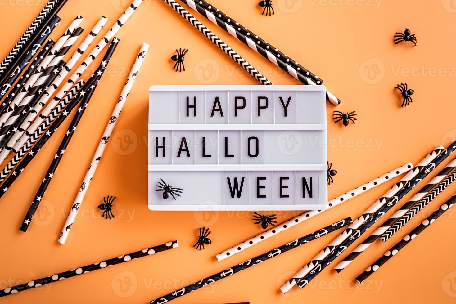 Feliz caja de luz de cine de Halloween con arañas y pajitas en blanco y negro vista superior sobre fondo naranja foto