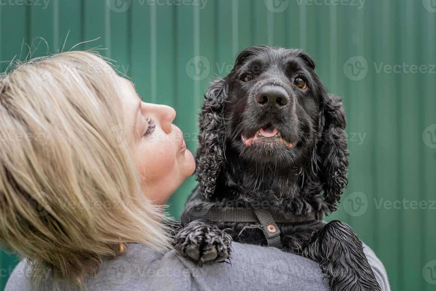 Mujer joven sosteniendo su perro cocker spaniel sobre fondo verde fuera foto