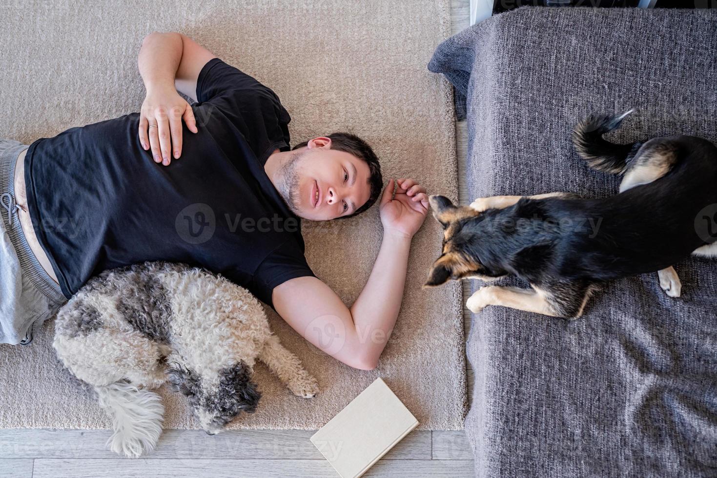 Young man lying on the floor at home with his dogs photo