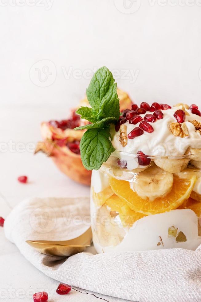 fruit salad with pomegranate, walnuts and fresh fruits in a jar on rustic concrete background front view photo