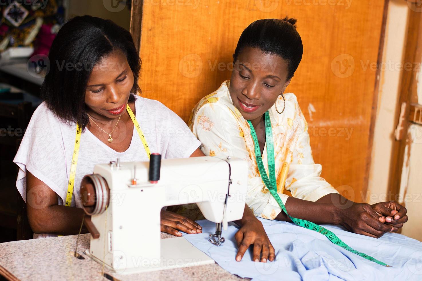 the student sews with her teacher in the workshop. photo