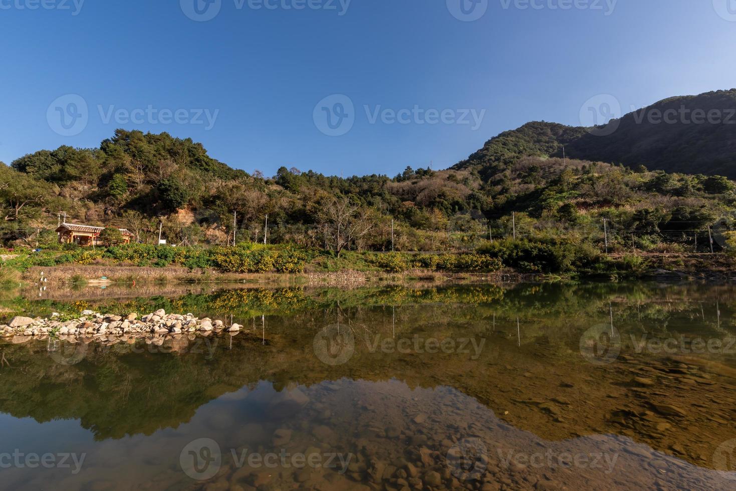 el río rural refleja la montaña, y las aldeas y los bosques están bajo el cielo azul foto