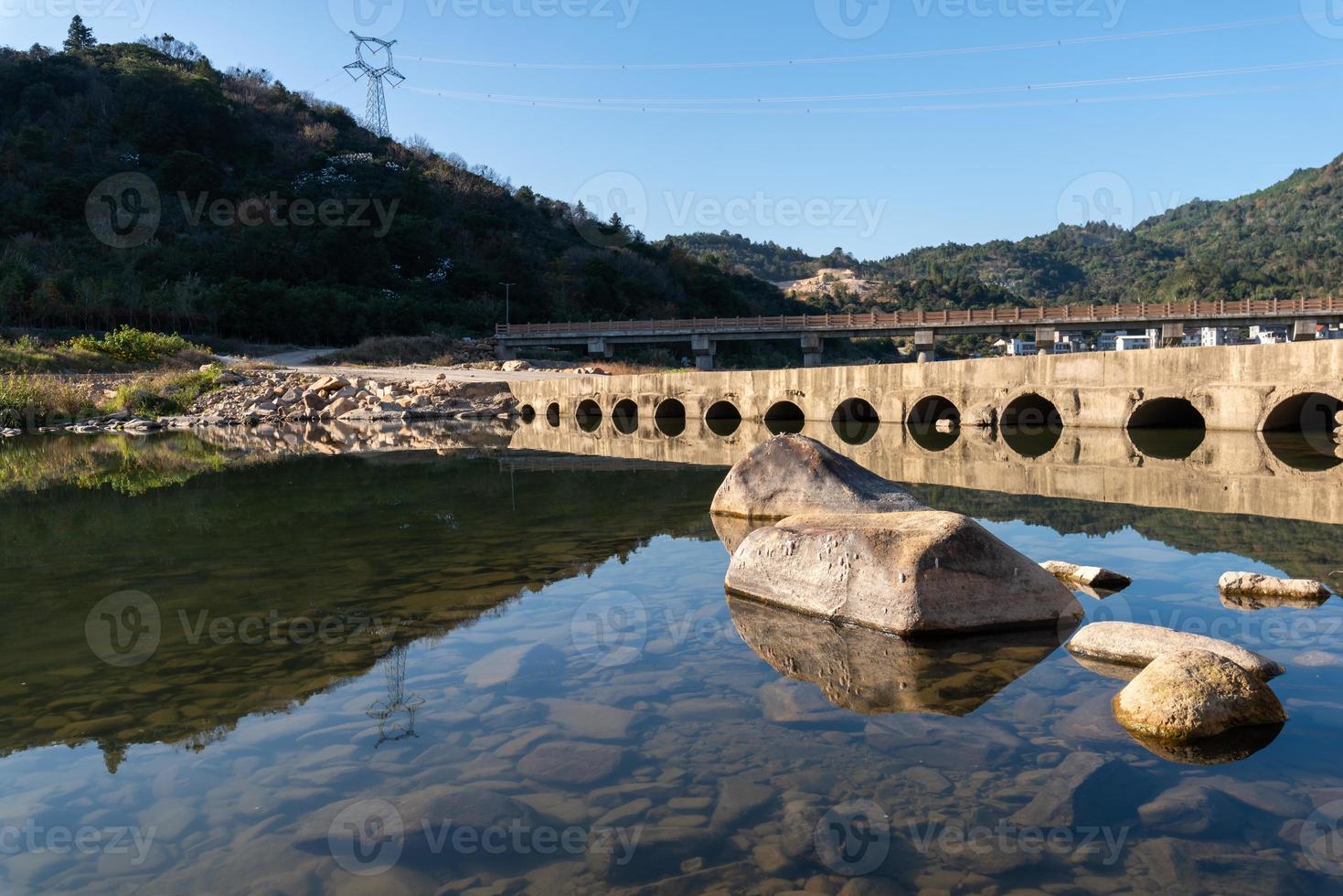 el río rural refleja la montaña, y las aldeas y los bosques están bajo el cielo azul foto