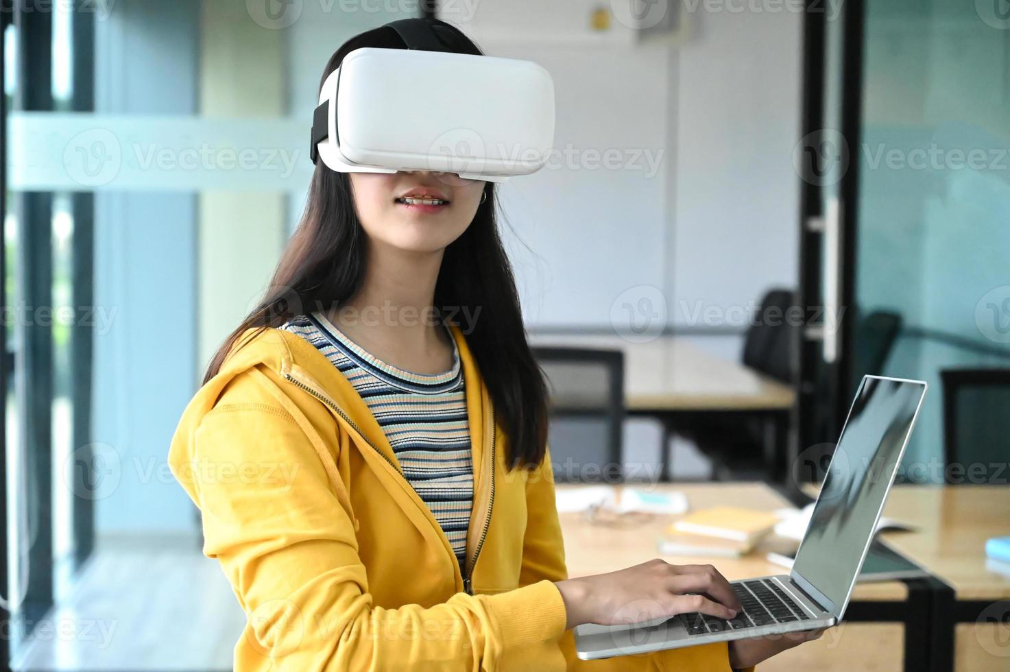 Captura recortada de una joven estudiante con gafas de realidad virtual y una computadora portátil. foto