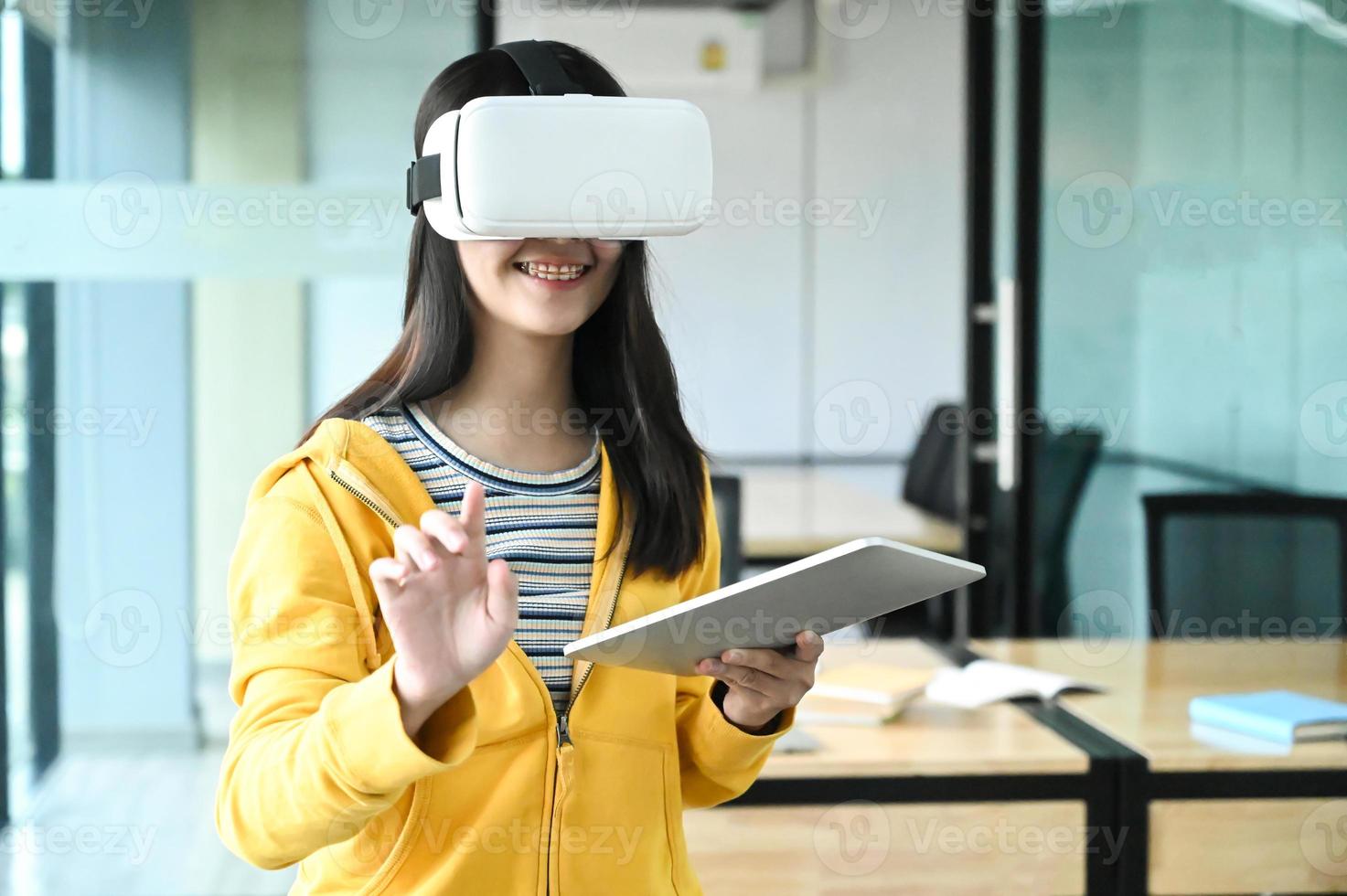 Cropped shot of a young female student wearing a VR glasses and using a laptop. photo