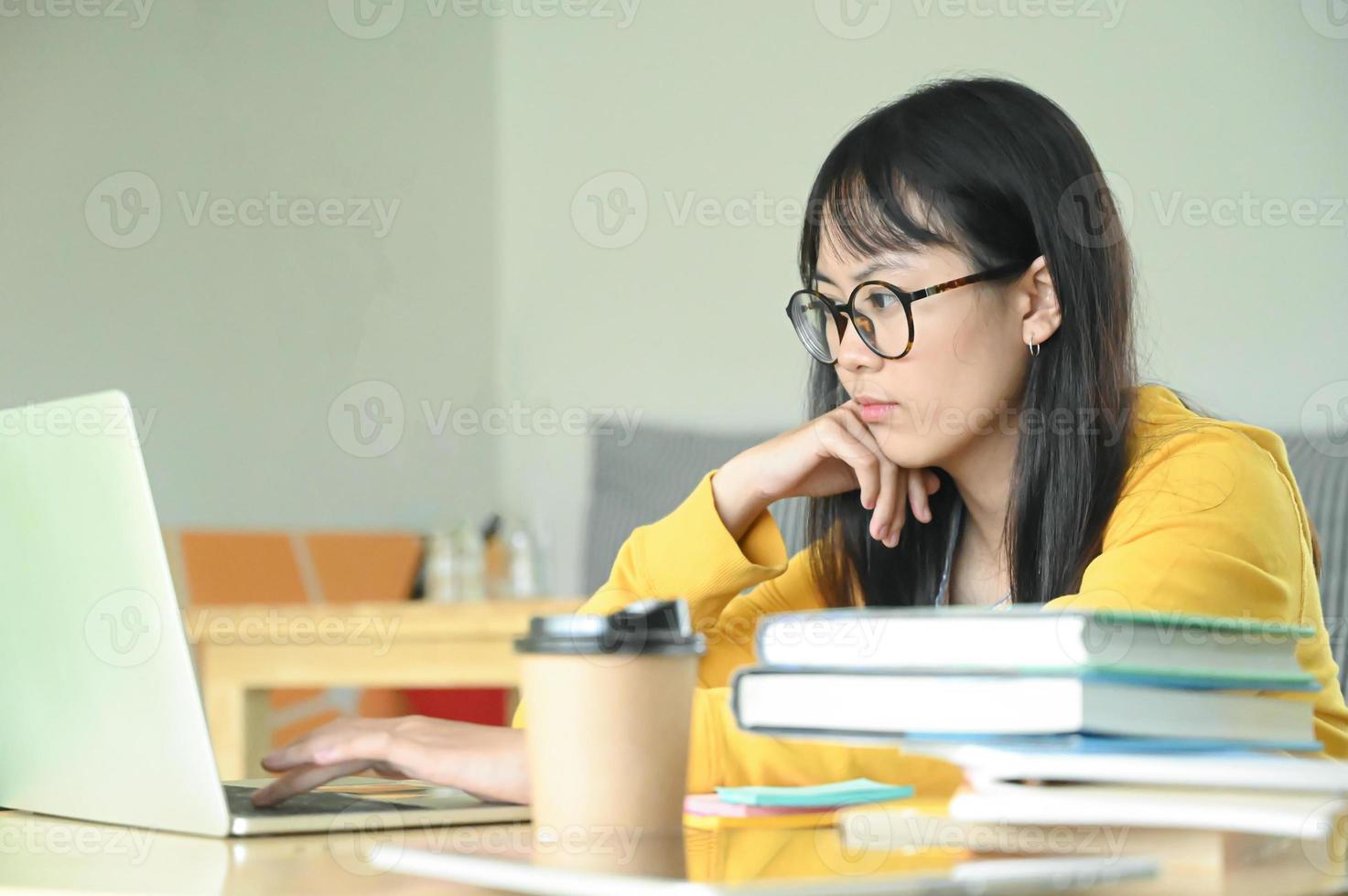 tazas de café y un cuaderno sobre la mesa con una estudiante adolescente están usando la computadora portátil en la parte posterior. foto