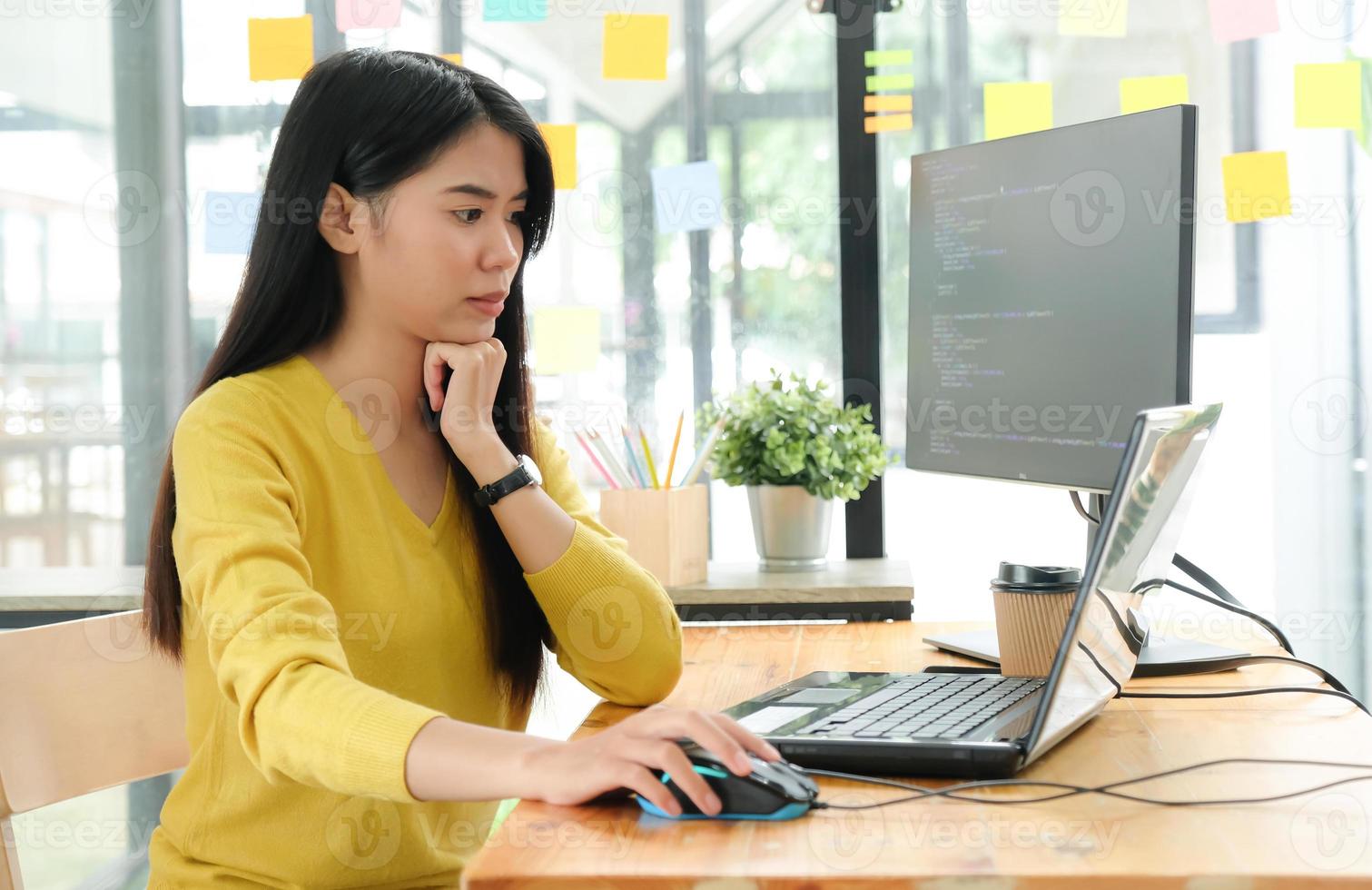 La programadora está usando una computadora portátil para crear programas para los clientes. Ella puso la mano en el mouse y la cara estaba seria. foto