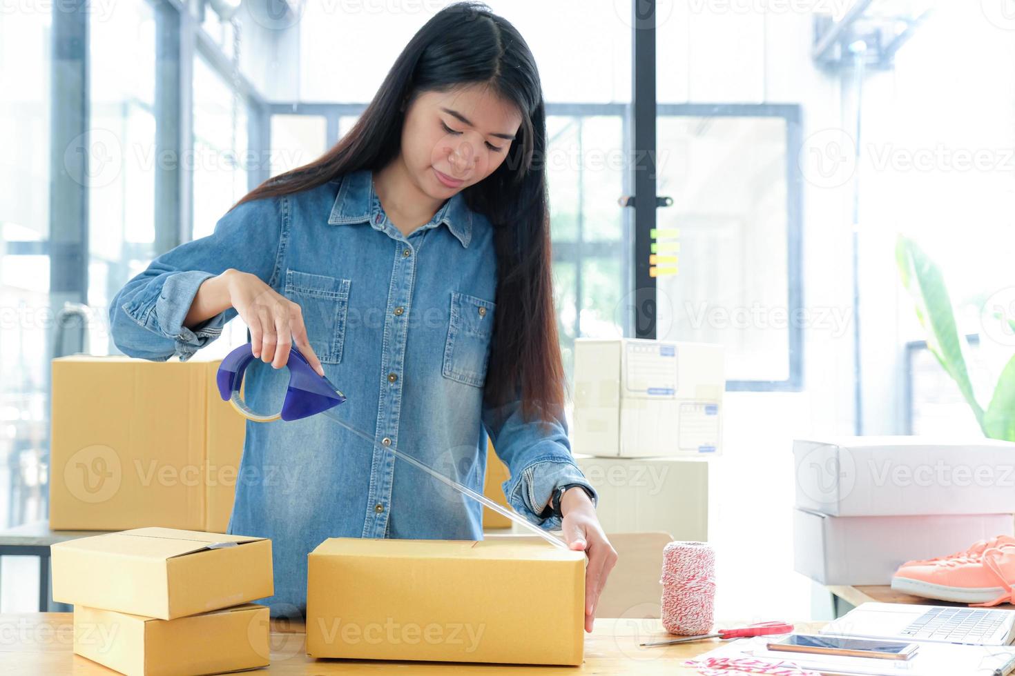 Teenage girls are packing products in boxes and using clear adhesive tape to deliver to customers. photo