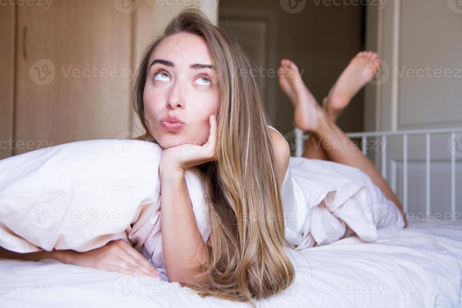 Close up Sexy young lazy lady lies on her stomach on the bed in delicate lingerie in the morning - Selective focus. Life style photo