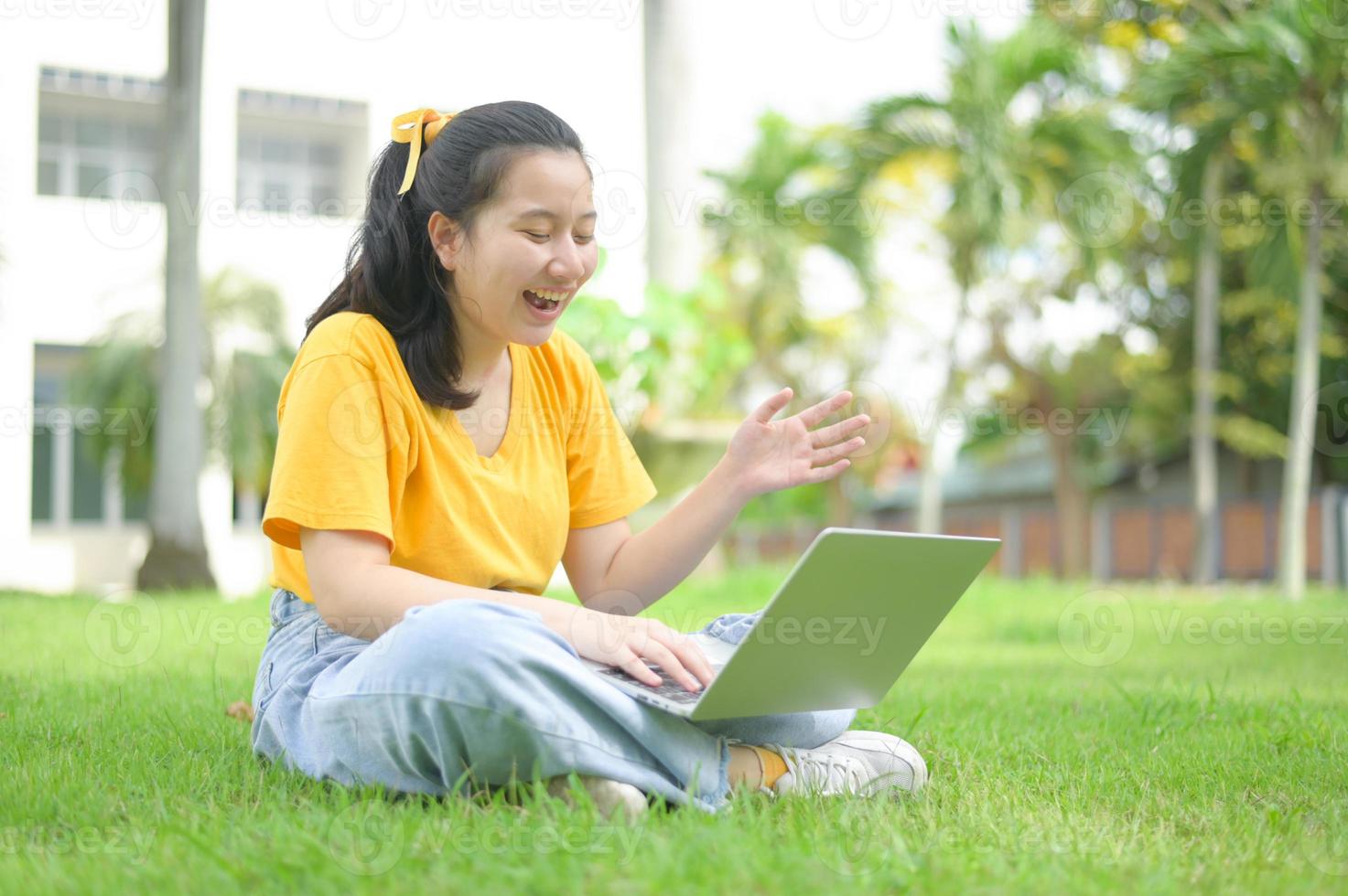 Young woman sitting on the lawn chatting with friends having fun on the lawn. photo