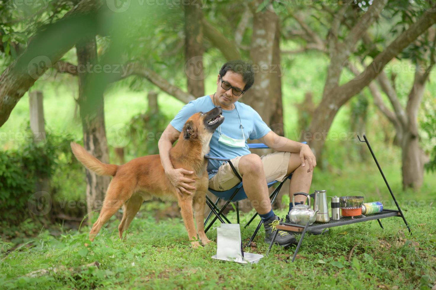 hombre descansando con perro durante el camping. foto