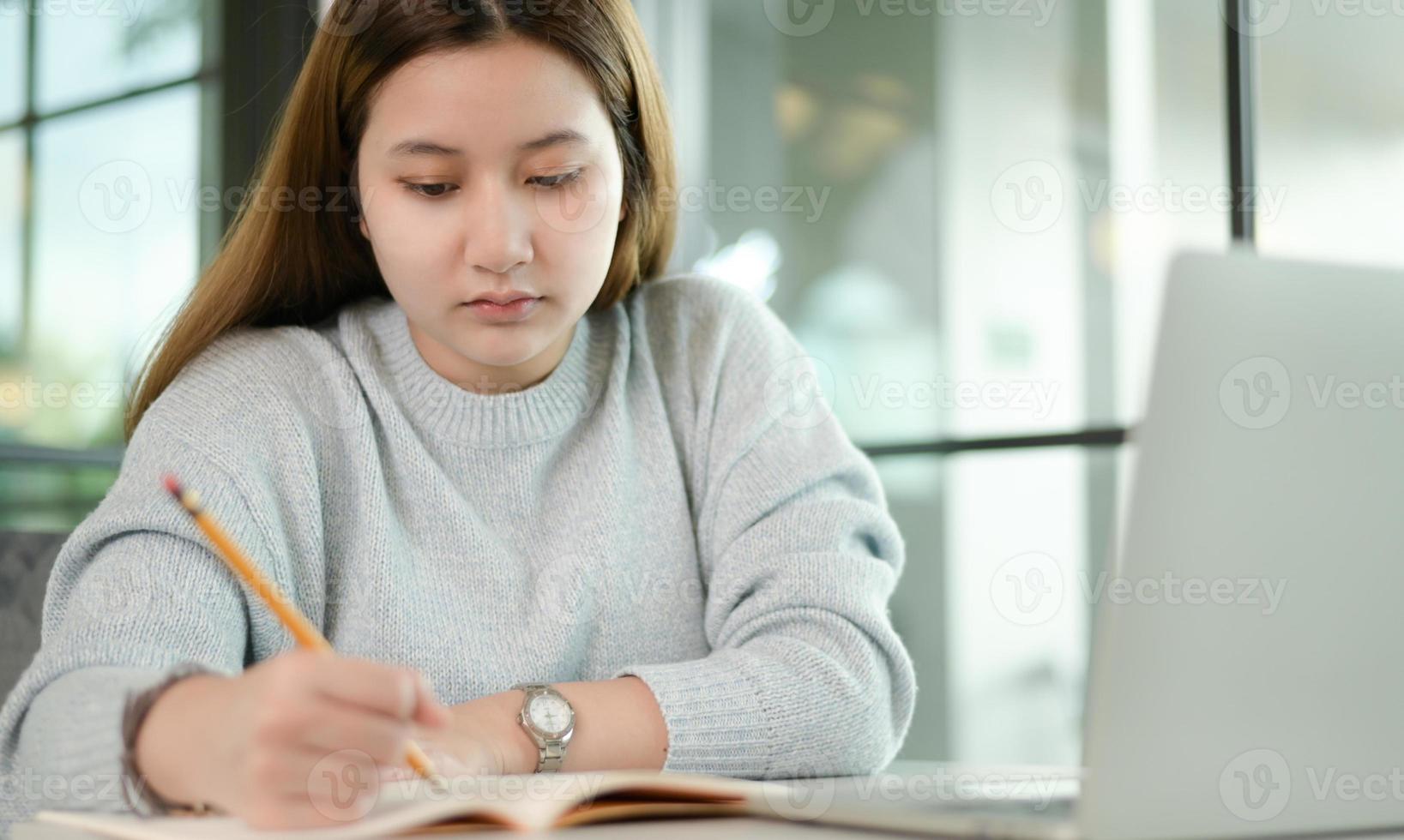 un estudiante universitario adolescente está tomando notas con diligencia. foto