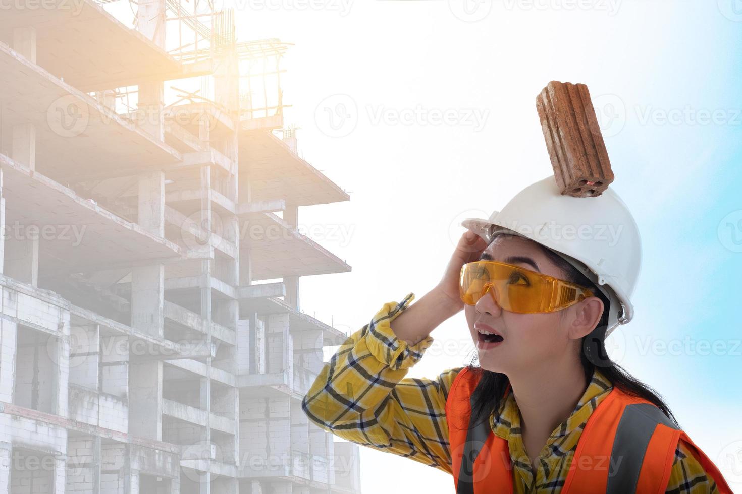 El ladrillo del bloque de palo cayó sobre la cabeza de la joven ingeniera de Asia sobre el trabajador del casco en el fondo blanco, el primer concepto de seguridad en la construcción del área foto