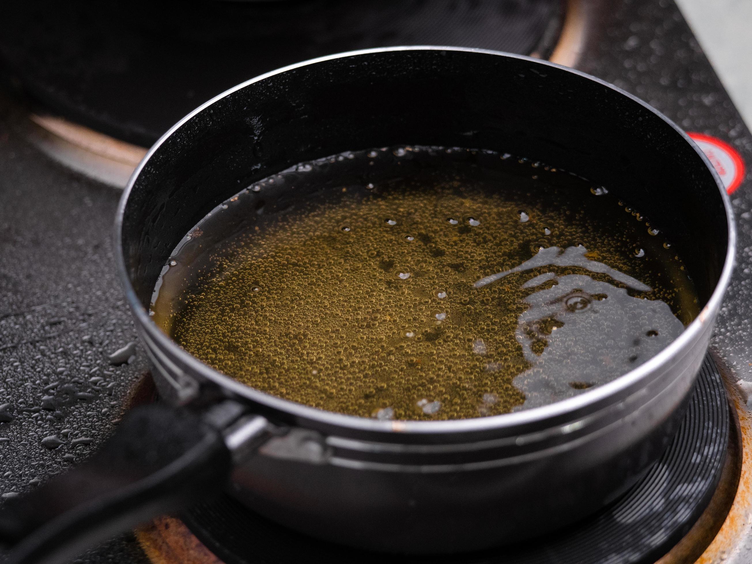 Close up of a pan of hot bubbling boiling oil on the electric stove in