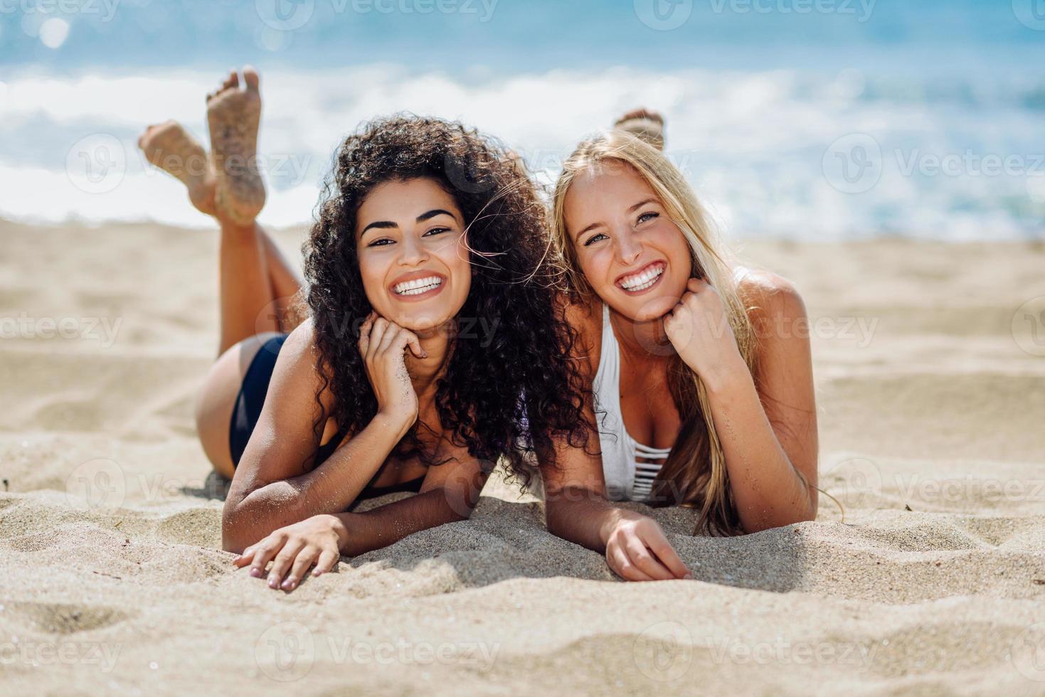 Two young women with beautiful bodies in swimsuit on a tropical beach photo